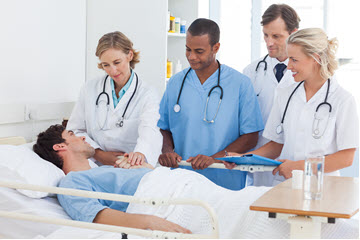man laying in hospital bed with doctors near bed side